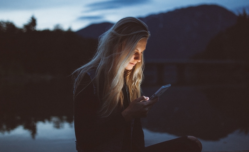 Tjej som håller sin telefon och tittar på skärmen